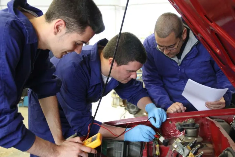 Alumnos de automoción trabajando en un motor con el profesor