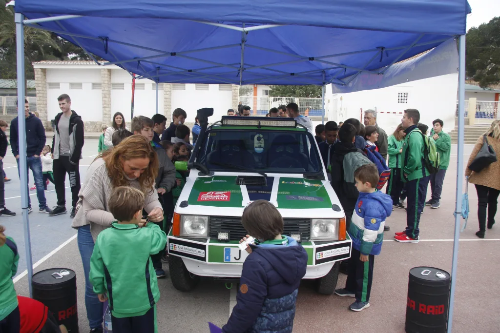 Familias y alumnos junto al Fiat Panda del Panda Raid, bajo una carpa en el patio del colegio