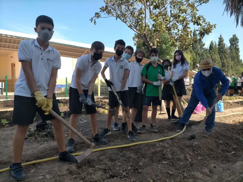 Alumnos de Primaria cavando el terreno del huerto ecológico L’Amighort