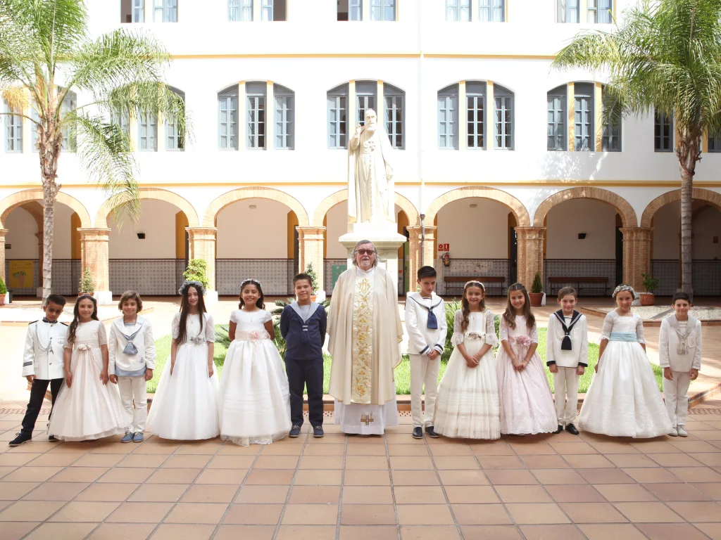 Grupo de alumnos de primera comunión con el sacerdote